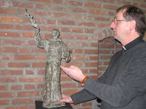 Pastoor Ron van den Hout poseert bij het beeld van de Heilige Franciscus in Hedel. Het beeld is van de hand van de Hedelse kunstenares Irene Janssen.